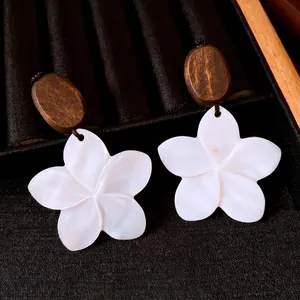 Élégantes boucles d'oreilles en nacre blanche et bois foncé sur présentoir en velours
