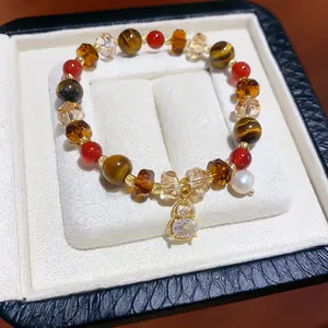 Close-up of vintage beaded bracelet with tiger eye stones and golden gourd pendant