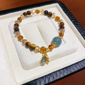 Detail view of a vintage tiger eye and crystal beaded bracelet in a white jewelry box.
