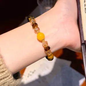 Close-up of a vintage Maillard style tiger eye and amber crystal beaded bracelet on a wrist
