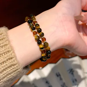 Macro detail of tiger's eye and amber crystal double-strand beaded bracelet on wrist.