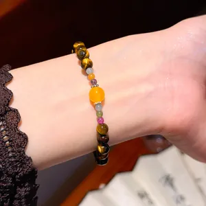Detail view of a retro tiger eye stone beaded bracelet with yellow agate on a woman's wrist.