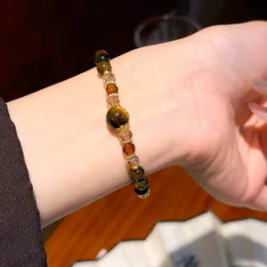 Detail view of a vintage tiger eye stone and crystal beaded bracelet worn on a wrist