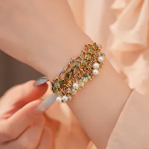 Close-up van een kleurrijke gevlochten touwarmband met groene zirkoon en parelkwastjes