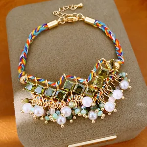 Close-up detail van een kleurrijke geweven boho armband met zirkoon en parel kwastjes