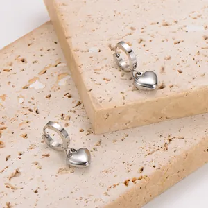 Detailed macro view of silver-toned stainless steel hoop earrings with heart pendant