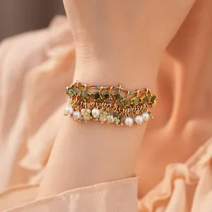 Detailopname van een boho armband met groene zirkoon en witte parelmoer franjes accent.
