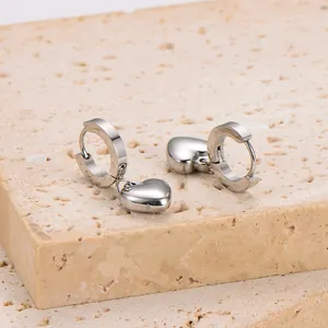 Close-up of minimalist stainless steel silver hoop earrings with heart charms