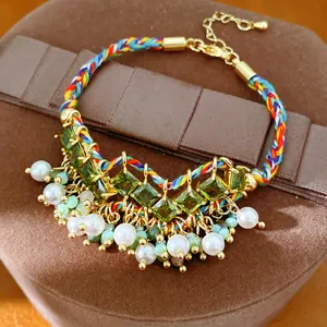 Gedetailleerd overzicht van gekleurde gevlochten armband met groene zirkoon en witte parels