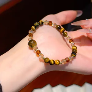 Close-up detail of a vintage tiger eye and crystal beaded bracelet on a woman's hand