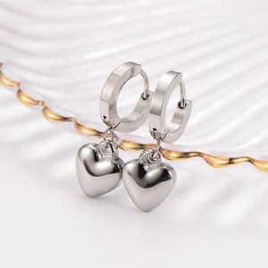 Detailed macro view of minimalist stainless steel silver heart pendant dangling hoop earrings