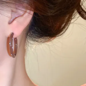 Makroansicht minimalistischer brauner Creolen mit Punkten im koreanischen Stil.