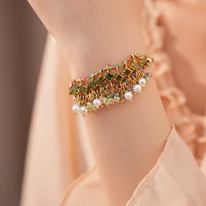 Detailweergave van een kleurrijke gevlochten armband met groene zirkonia en parels om de pols