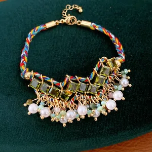 Close-up van gevlochten regenboog armband met groene zirkonia en witte parels