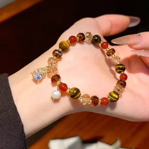 Close-up of retro tiger eye and crystal beaded bracelet with pearl charm on hand.