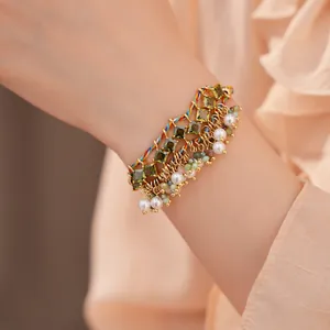 Close-up van een kleurrijke geweven etnische armband met groene zirkonen en parels aan de pols