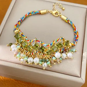 Detail van kleurrijke gevlochten armband met groene zirkonia stenen en witte parels