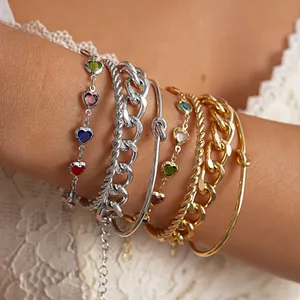 Macrodetail van een 4-delige metalen armbandset met gekleurde glazen hartkralen en knoopring