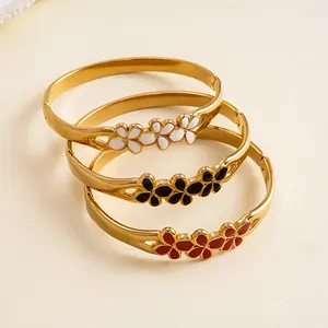 Vue détaillée de trois bracelets en acier doré avec motifs de fleurs en émail coloré