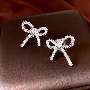 Élégants clips d'oreilles nœud en argent avec zircons étincelants sur boîte à bijoux