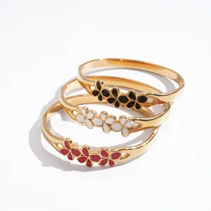 Élégants bracelets joncs en acier doré avec fleurs émaillées en noir, blanc et rouge