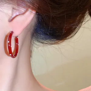 Detailansicht einer roten Creole mit weißen Punkten auf dem Modellohr aus Emaille