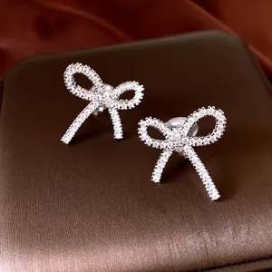 Detailed macro view of sparkling cubic zirconia bow earrings on a brown jewelry box