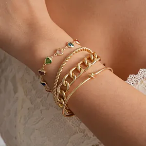 Detailopname van een vierdelige gouden armbandset met hartvormige kleurrijke stenen