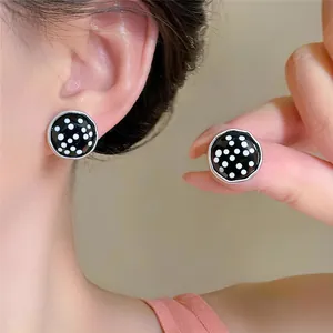 Detailansicht der runden Retro-Ohrstecker mit schwarz-weißen Punkten an einem Modelohr