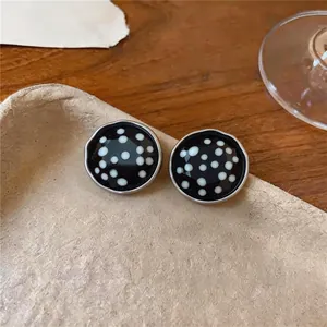 Detailansicht der runden Retro-Ohrstecker mit elegantem schwarz-weißen Punktmuster