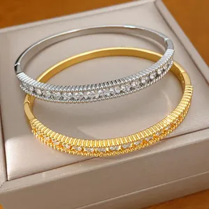 Detailansicht eleganter Gold- und Silberarmreifen mit funkelnden Zirkonia auf Schmuckbox