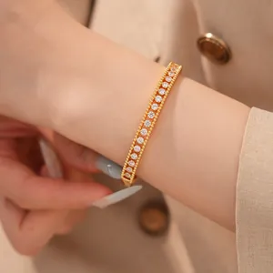 Nahaufnahme eines 18K vergoldeten Doppelarmreifs mit funkelnden Zirkonia am Handgelenk.