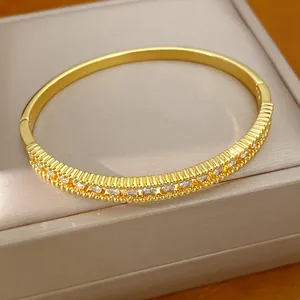Detailansicht eines 18K vergoldeten Armreifs mit geripptem Design und funkelnden Zirkonen.
