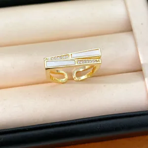 Detailansicht eines goldenen geometrischen Rings mit weißen Einlagen und Zirkonia