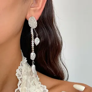 Nahaufnahme von Vintage Metall-Ohrringen mit Barockperlen-Quasten und Spitzen-Details