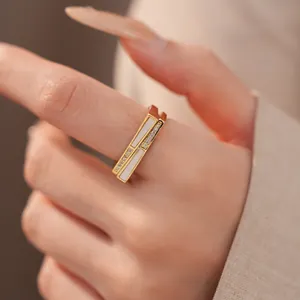 Nahaufnahme eines goldenen geometrischen Rings mit Inlays und Zirkonia am Finger