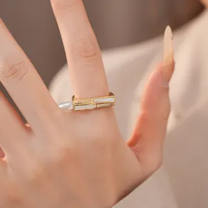 Detailansicht eines geometrischen Goldrings mit weißen Muscheleinlagen und Zirkonia