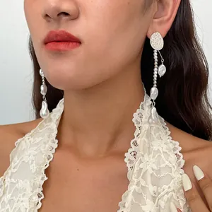 Nahaufnahme von Retro-Silberohrringen mit Perlen und Quasten an einem Model in Spitze.