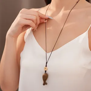 Primo piano del ciondolo a pesce in legno su collana in corda intrecciata artigianale