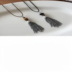 Detailed macro shot of stainless steel tassel necklace featuring stone and shell beads