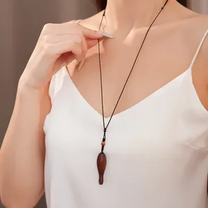Dettaglio di una collana artigianale in legno a forma di pesce indossata da una modella