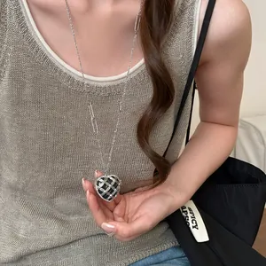 Vue détaillée d'un collier pendentif cœur argenté avec un motif en strass.