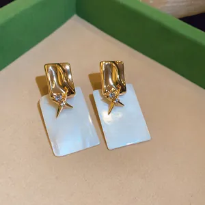 Détail de boucles d'oreilles élégantes plaquées or 18 carats avec zircon et nacre.
