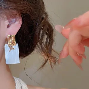 Détail de boucles d'oreilles carrées en nacre plaquées or 18k avec étoile en zircon