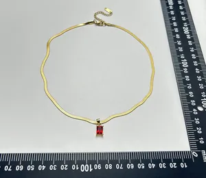 Detailopname van vergulde slangenketting met vierkante rode zirkonia hanger.