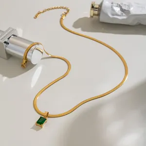 Detail van een 18K vergulde slangenketting met een rechthoekige groene zirkoon