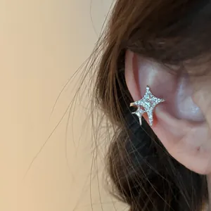 Close-up of star-shaped zircon ear cuff on ear bone, 14K gold plated silver finish jewelry.