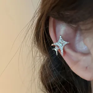 Detailed close-up showing a sparkling zircon star-shaped ear cuff worn on a person's ear