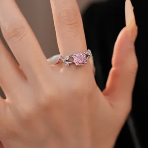 Close-up of an elegant pink circular zircon ring with delicate leaf accents on hand