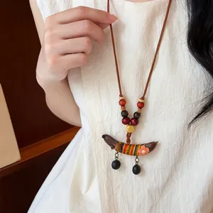 Detailopname van een etnische houten kralenketting met een kleurrijke stoffen erwtenhanger.